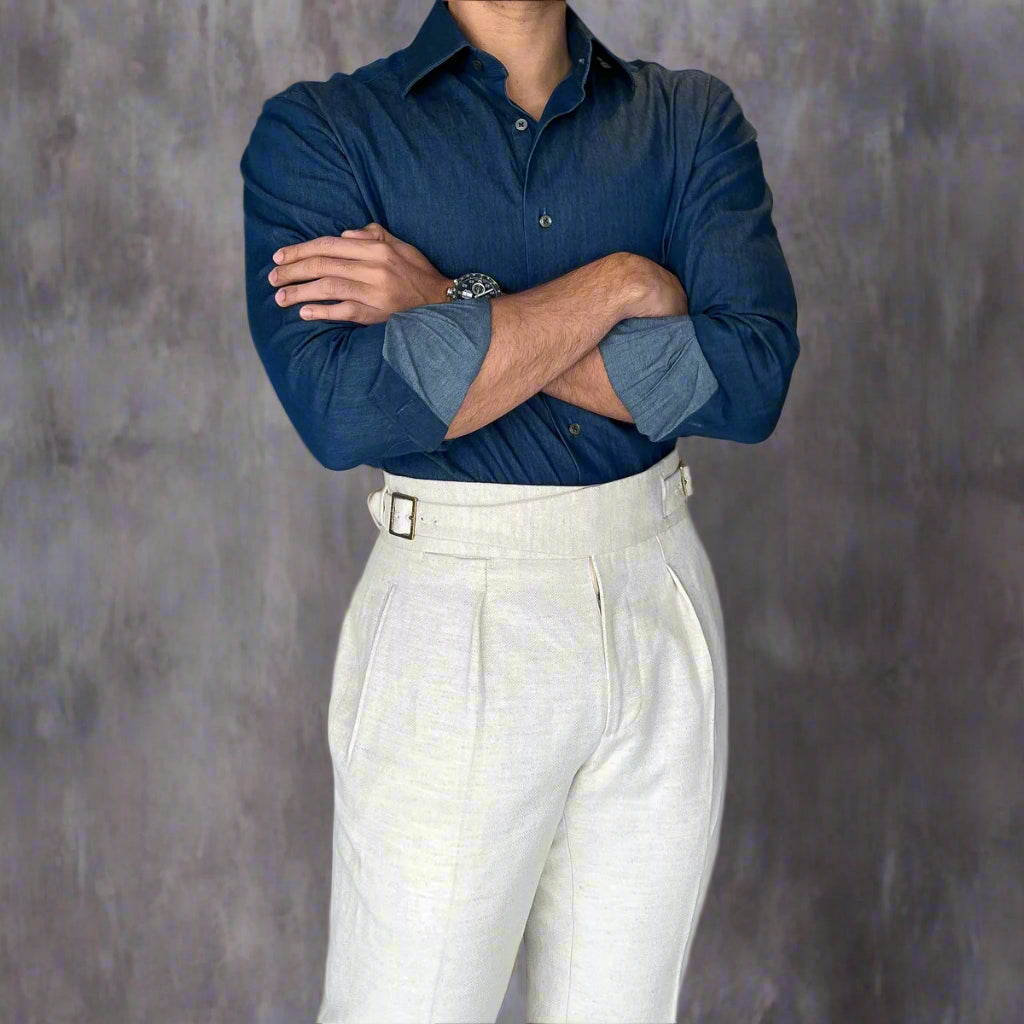 Person wearing a blue shirt and white pants standing indoors.